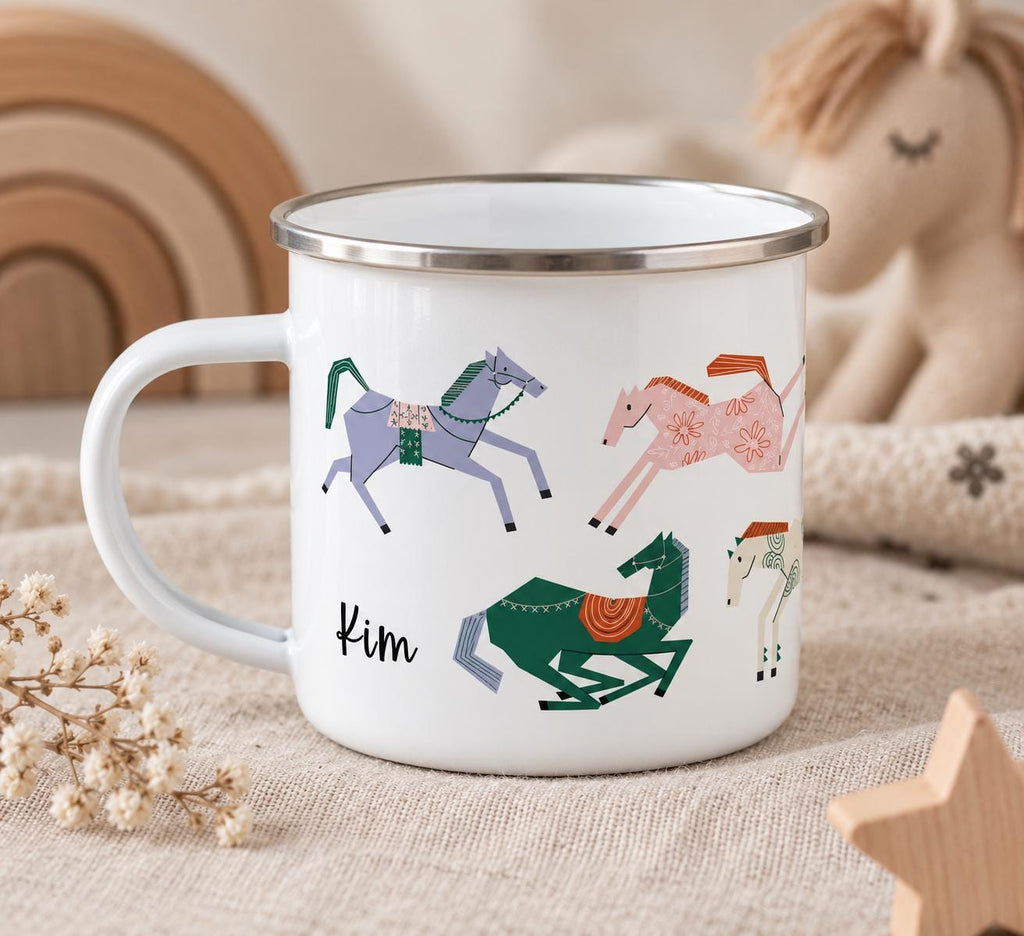 A white enamel mug with a silver-toned rim featuring a colourful graphic print of four stylised horses in shades of purple, pink, green, and cream. The name Kim is printed in black script lettering on the side of the mug.