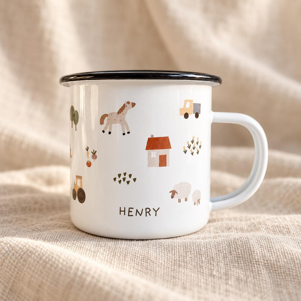 A white enamel mug with a black rim and handle, featuring a farm-themed pattern of a horse, a house, a truck, a tractor, sheep, and trees. The name HENRY is printed in black capital letters on the front of the mug.