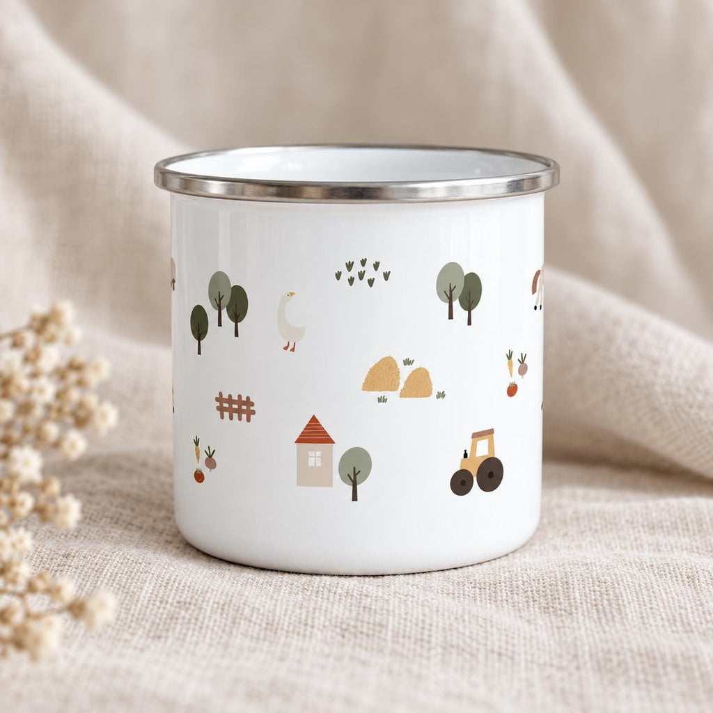 A white enamel mug with a silver-toned rim featuring a repeating pattern of farm-themed illustrations including a small house with a red roof, a yellow tractor, a white goose, green trees, hay bales, a brown fence, and vegetables.