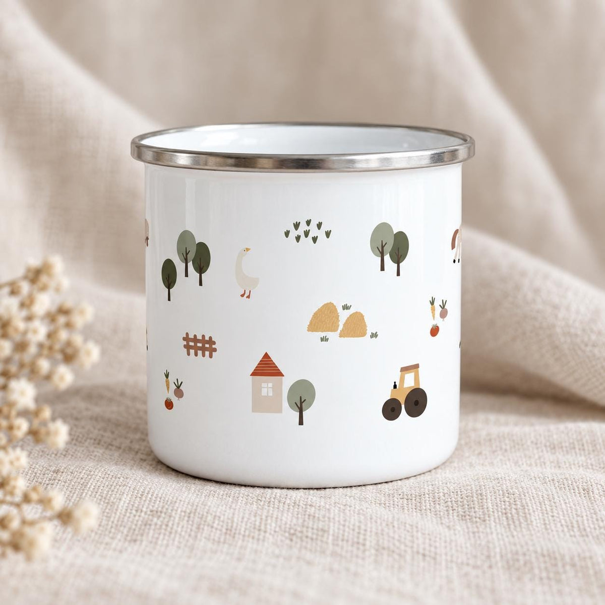 A white enamel mug with a silver-toned rim featuring a repeating pattern of farm-themed illustrations including a small house with a red roof, a yellow tractor, a white goose, green trees, hay bales, a brown fence, and vegetables.