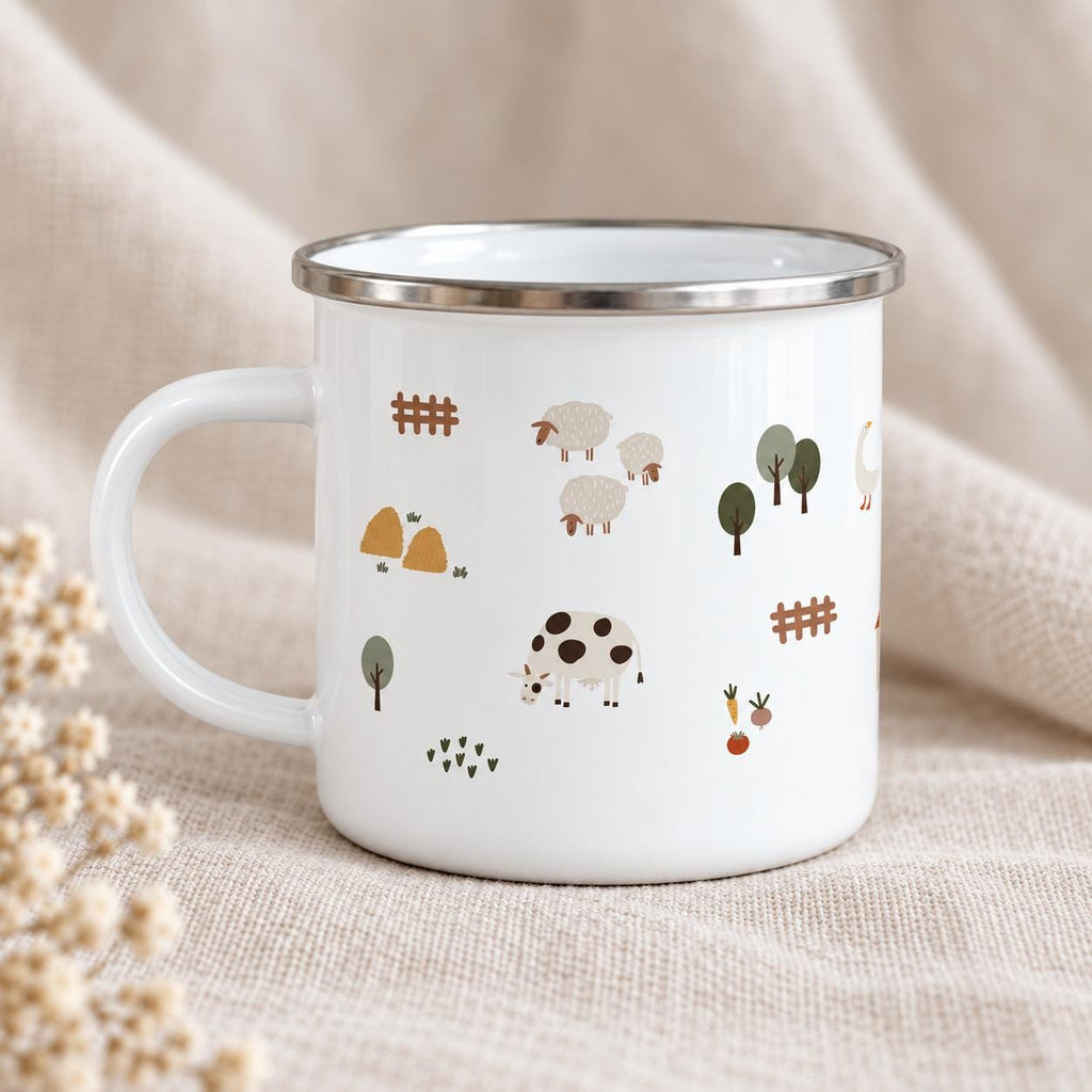 A white enamel mug with a silver rim and a handle, featuring a repeating pattern of farm-themed illustrations including sheep, a cow with black spots, brown fences, green trees, haystacks, a goose, and small garden vegetables.
