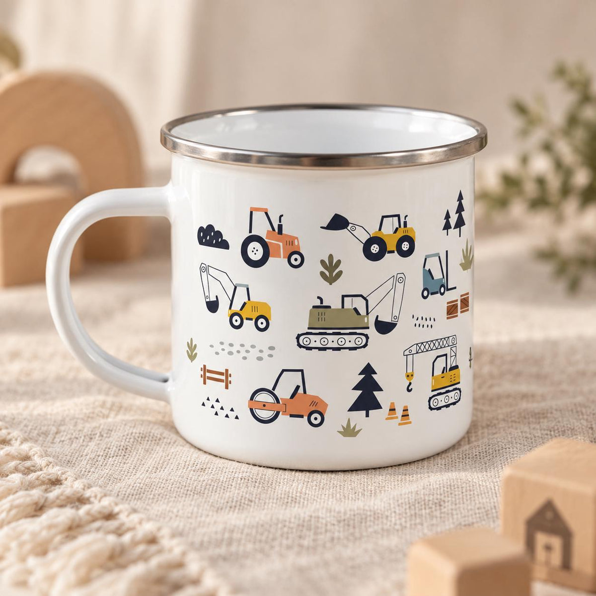 A white enamel mug with a silver rim featuring a repeating pattern of construction vehicles including tractors, excavators, a crane, and a road roller, interspersed with small trees, traffic cones, and various geometric shapes.