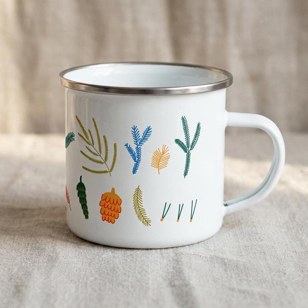 Side view of the botanical enamel mug displaying the handle on the right and evergreen pattern.