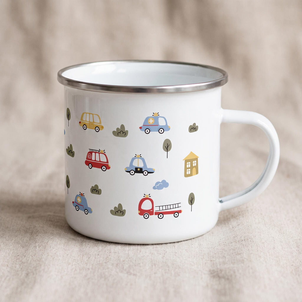 A white enamel mug with a handle on the right, decorated with small illustrations of cars, trees, and houses.