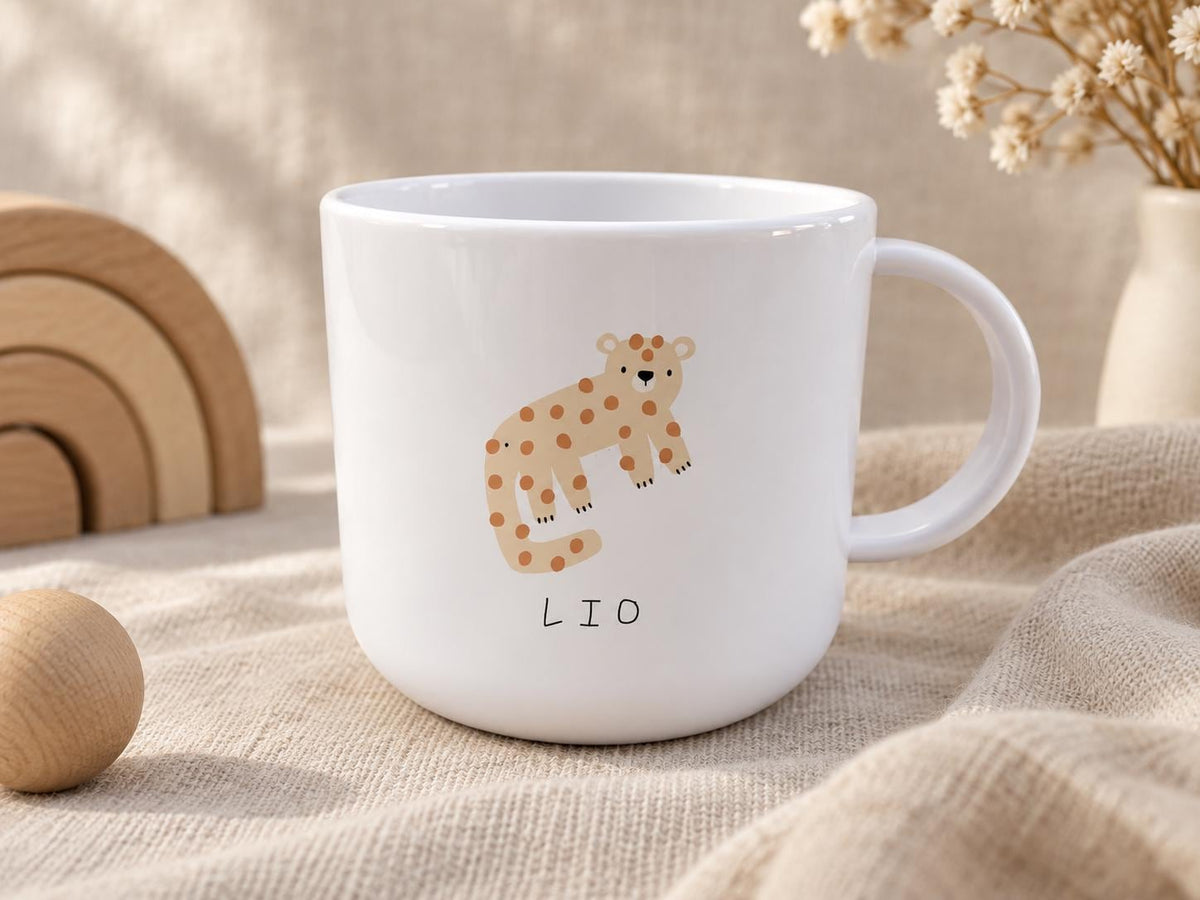 A white kids cup featuring a graphic illustration of a tan leopard with brown spots. Below the leopard, the name LIO is printed in simple black capital letters. The cup has a smooth, rounded body and a curved handle on the right side.