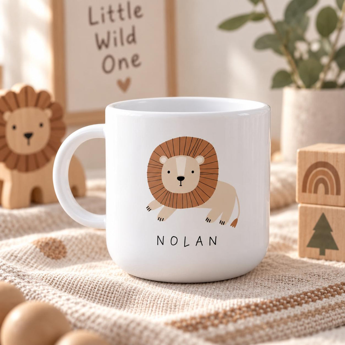 A white kids cup featuring a graphic illustration of a lion with a brown mane and the name NOLAN printed in black capital letters below the lion. The cup has a curved handle and a smooth, glossy finish on the exterior surface.