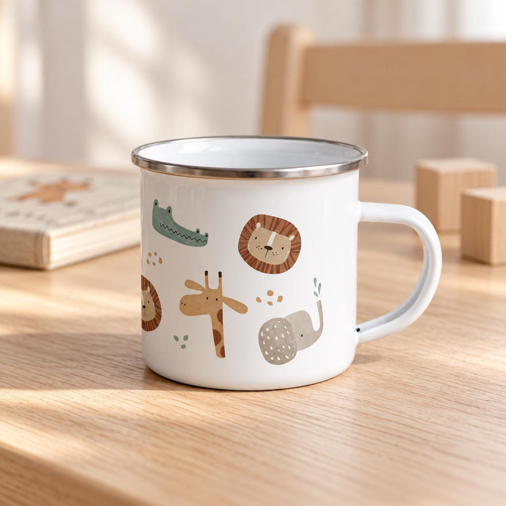 Safari animal enamel mug with a silver rim on a pale wooden children’s table. A picture book, wooden blocks and a small chair create a softly lit Scandinavian playroom setting behind the mug.