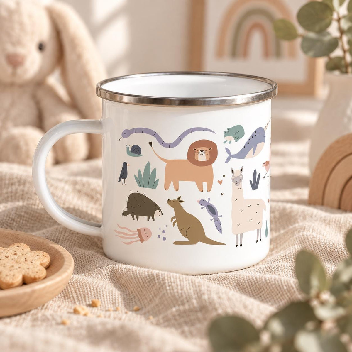 A white enamel mug with a silver rim featuring a colourful graphic print of various animals including a lion, kangaroo, llama, narwhal, snake, snail, and jellyfish. The mug has a curved handle and a smooth, glossy finish on the exterior.
