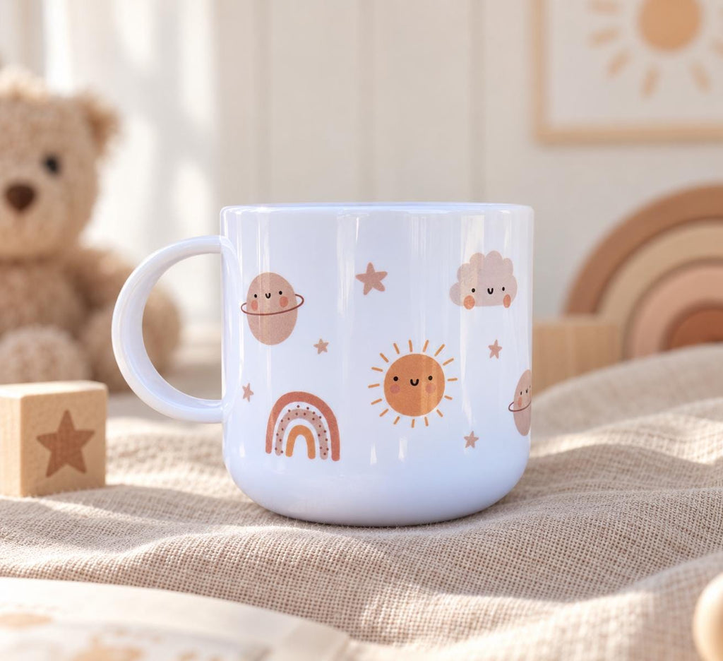 A white cup featuring a repeating pattern of cute, smiling celestial icons including a sun, planets, a rainbow, clouds, and small stars in soft shades of brown, peach, and cream. The cup has a smooth finish and a curved handle.