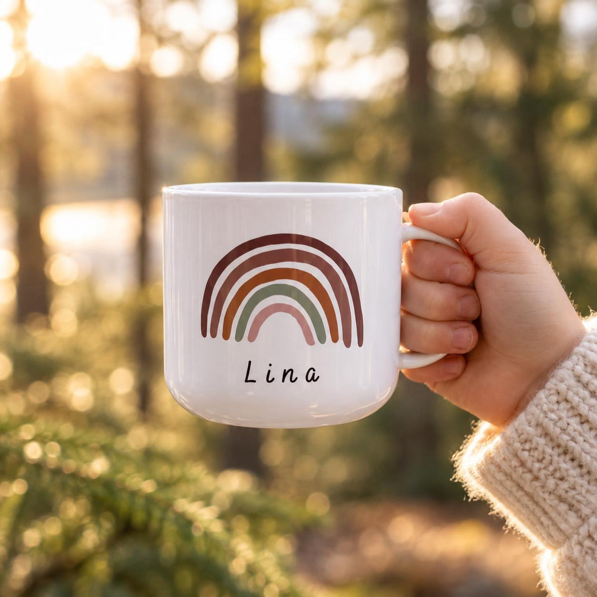 A white kids cup featuring a printed graphic of a multi-coloured rainbow in shades of brown, terracotta, sage green, and dusty pink. The name Lina is printed in a simple black sans-serif font directly below the rainbow illustration.