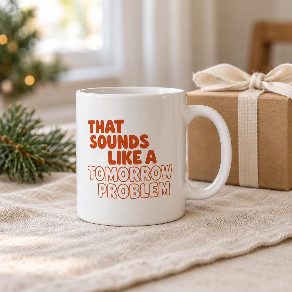 Tomorrow Problem mug next to a kraft gift box with a cream ribbon and pine sprigs on a linen cloth.