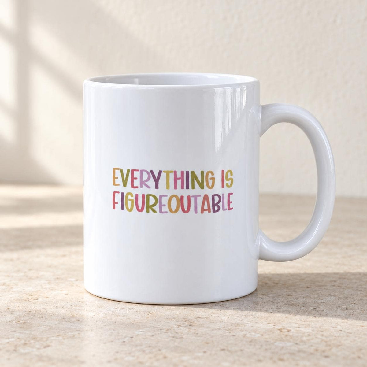 Everything Is Figureoutable ceramic mug on a beige linen tablecloth.
