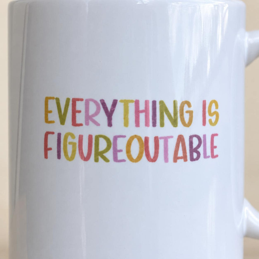 Close-up of the colourful Everything Is Figureoutable print on a white mug.